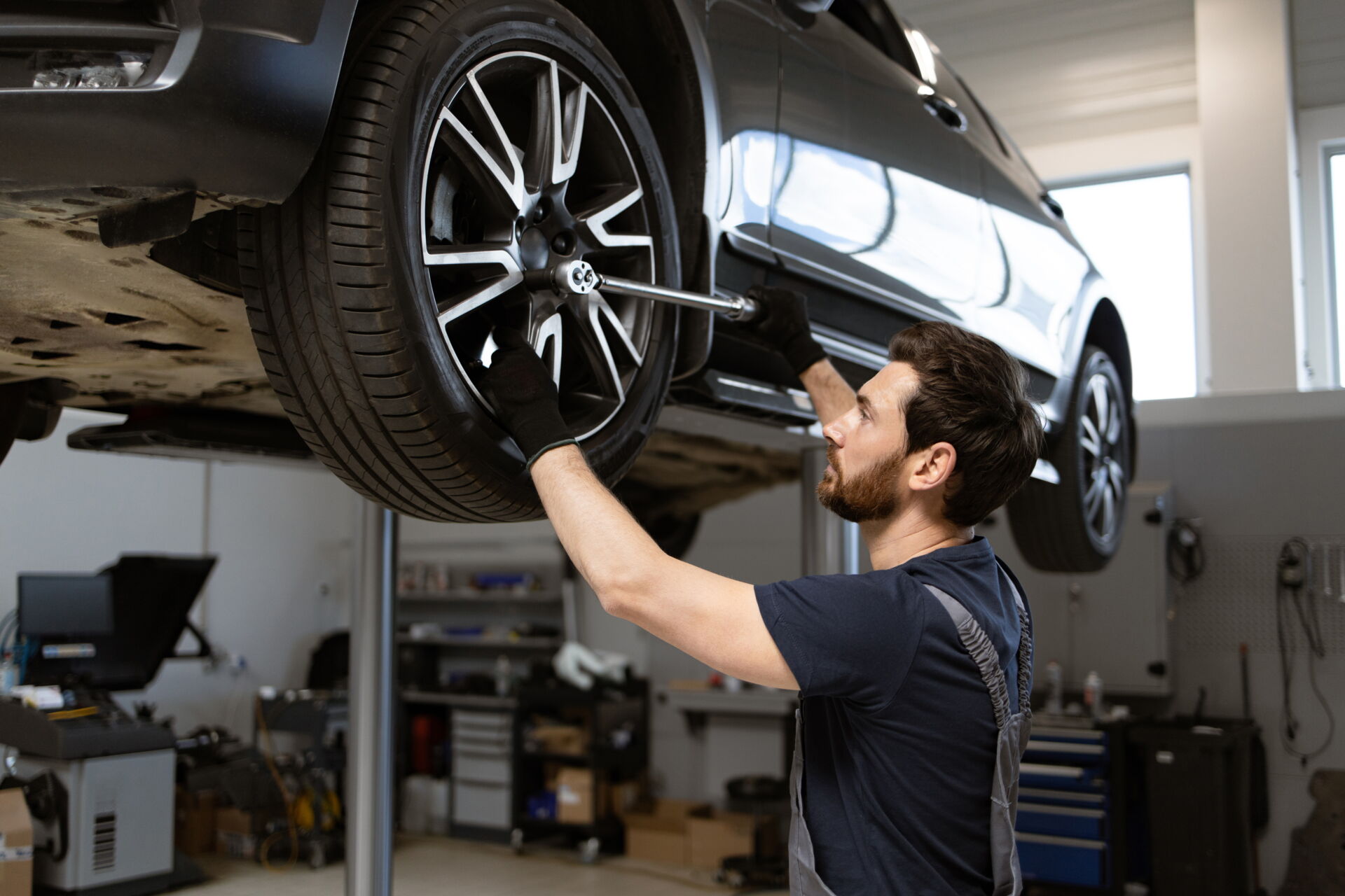 Ein Mechaniker wechselt einen Reifen an einem aufgebockten Auto in einer Werkstatt. Reifendienst Böhme in Vetschau bietet professionellen Reifenservice.